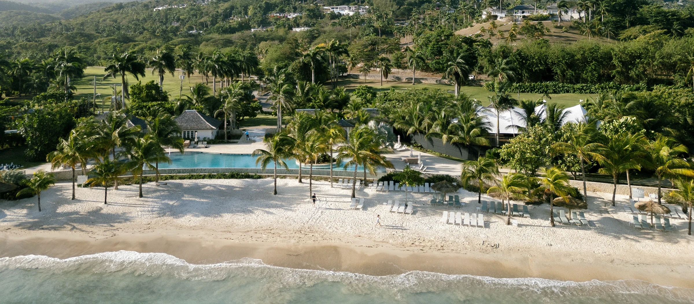 Aerial panorama of the Tryall Club — palm groves, infinity pool, and a mile of private beach
